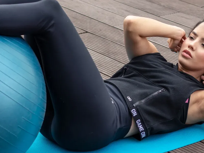 A woman doing crunches with her legs resting on a stability ball