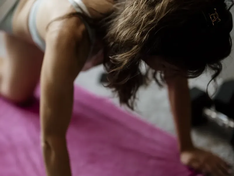 A woman in a plank position on an exercise mat at home