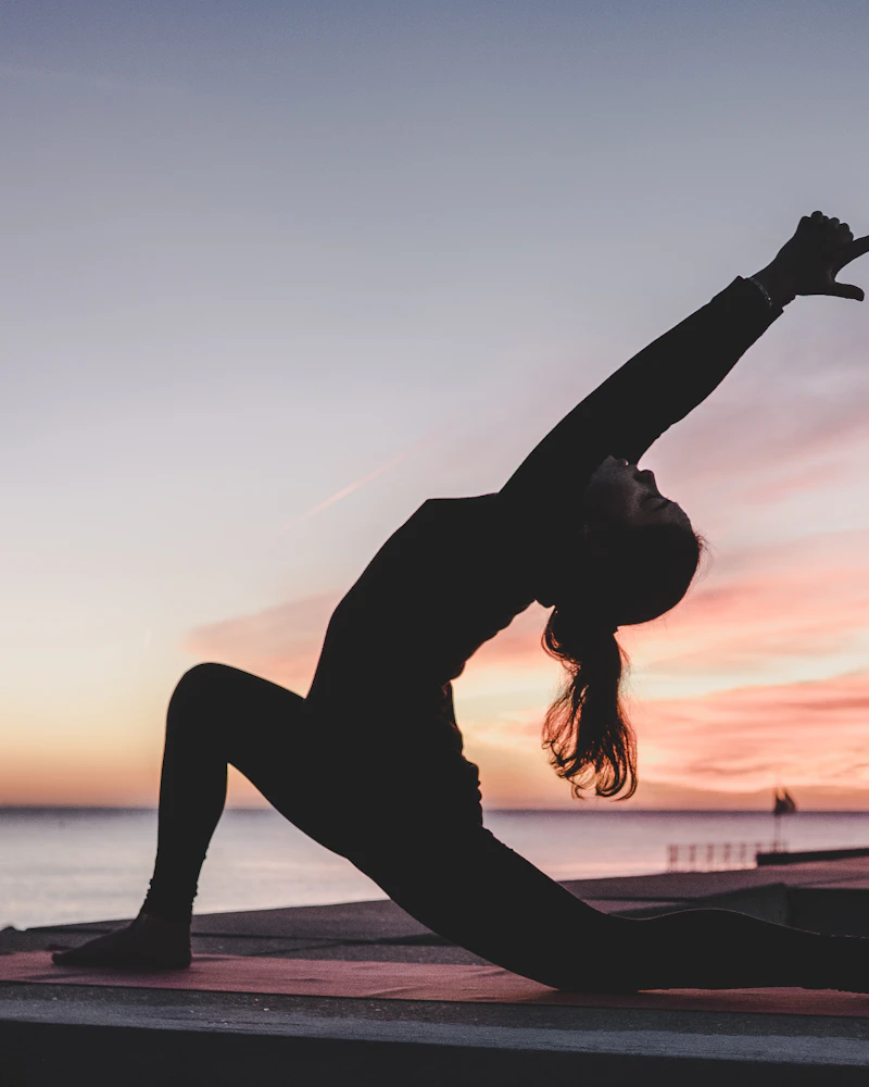 A woman stretching in a low lunge at sunset